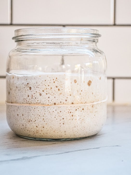 A jar of sourdough starter with a rubber band around it