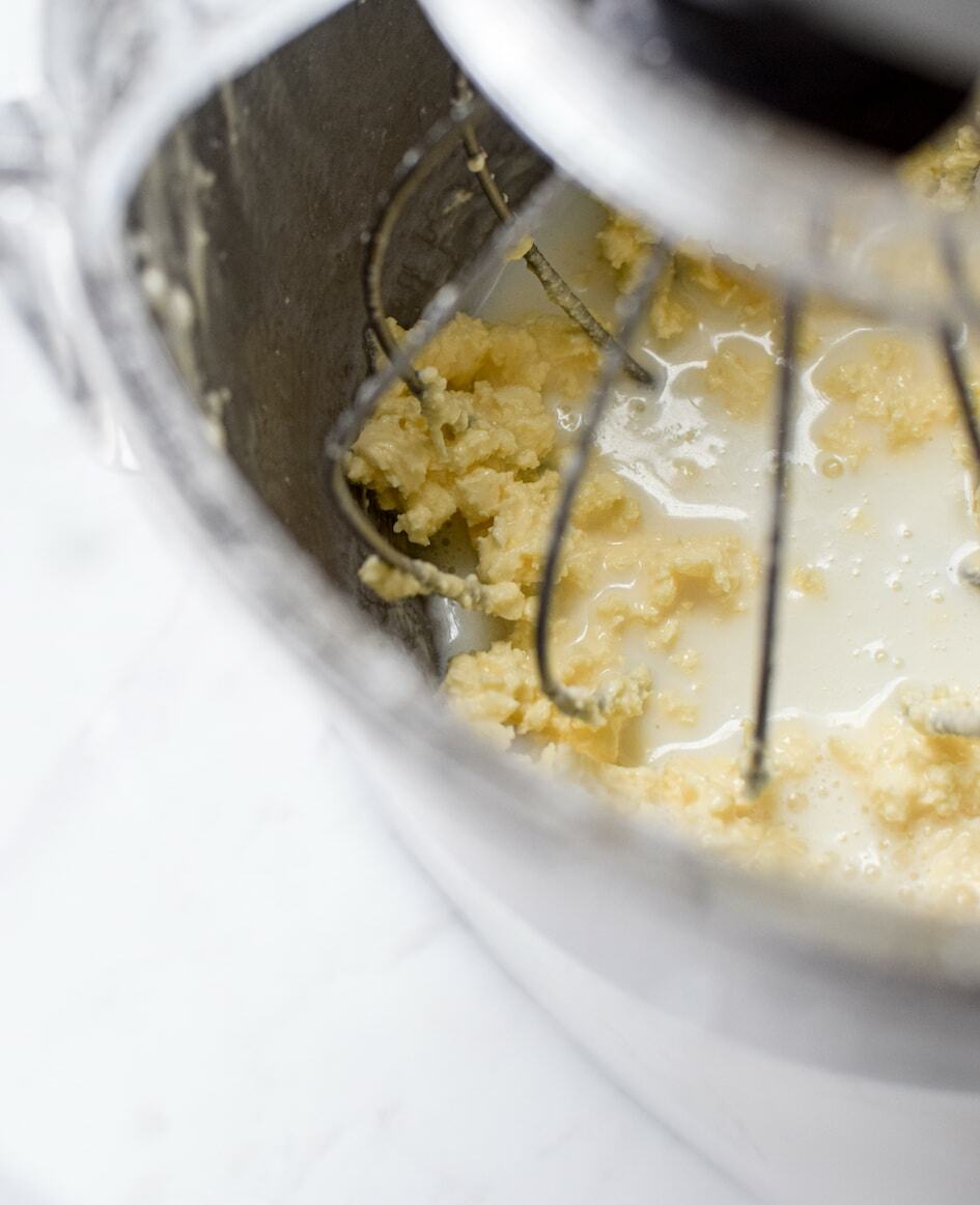 yellow clumps of butter being formed while being mixed inside a stand mixer 