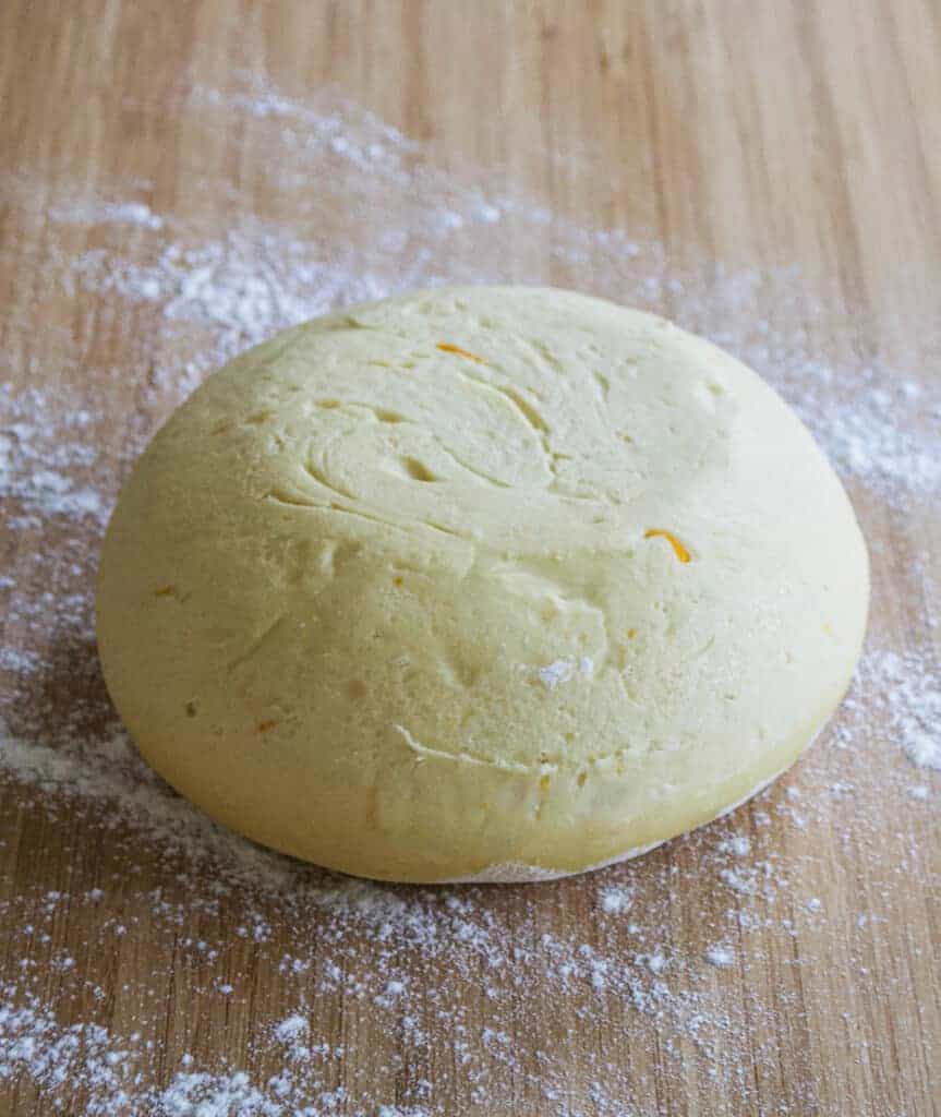 a ball of dough on a floured wooden bench
