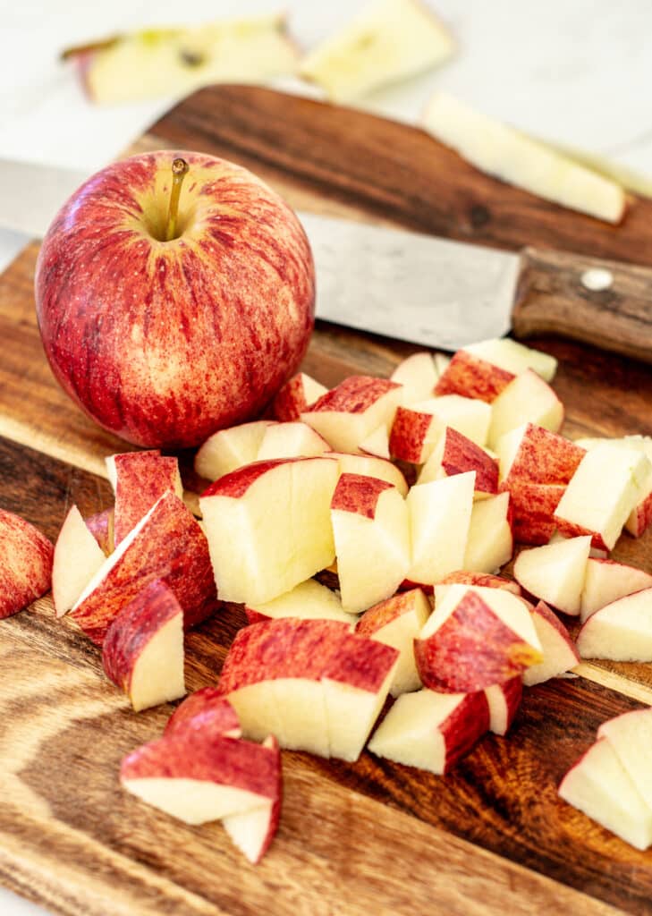 chopped apple on a wooden board with a brown knife in the background
