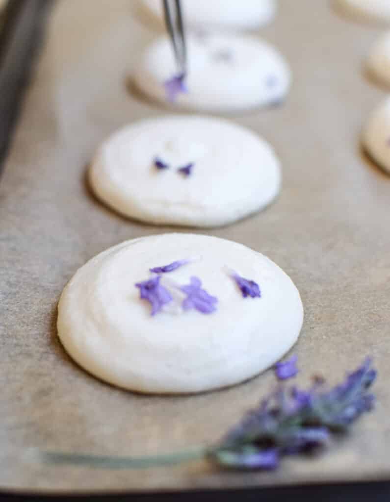 lavender flowers being placed on macarons