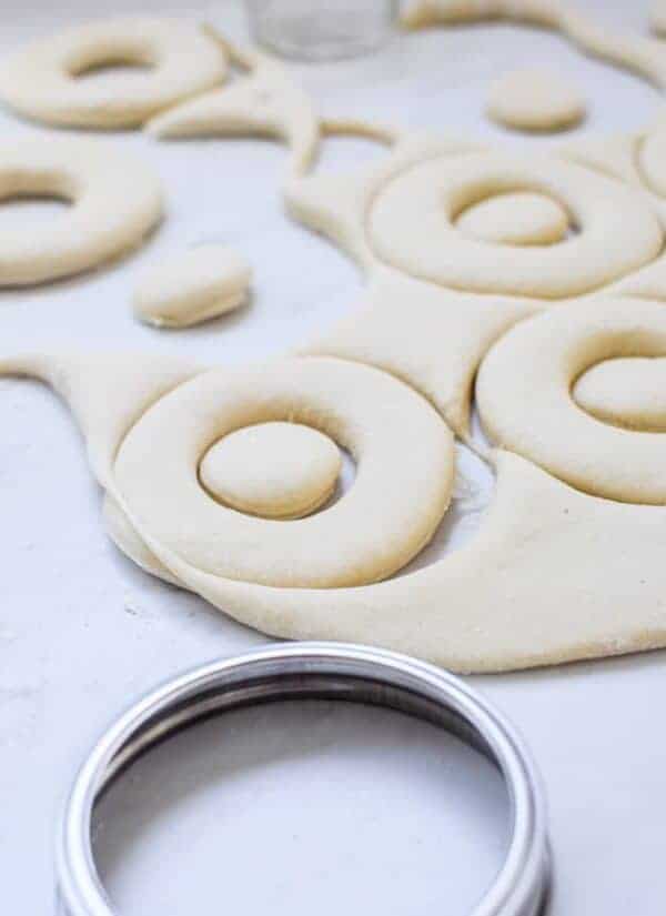 donut shapes cut out of dough with a silver jar lid