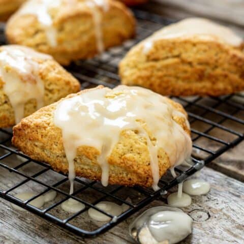 orange scones dripping with glaze. An orange is in the background.