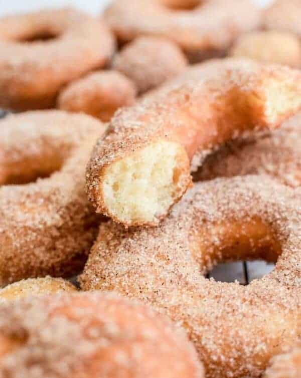 a stack of donuts with one cut in half, dusted in cinnamon sugar