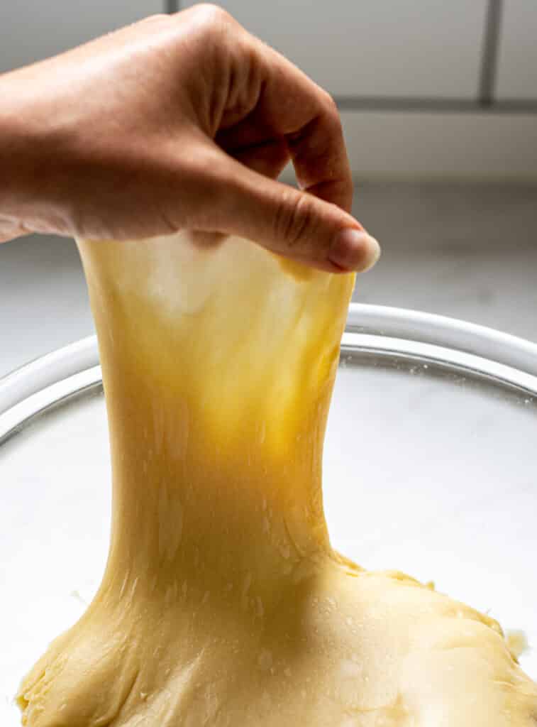 dough being stretched very thin in a glass bowl