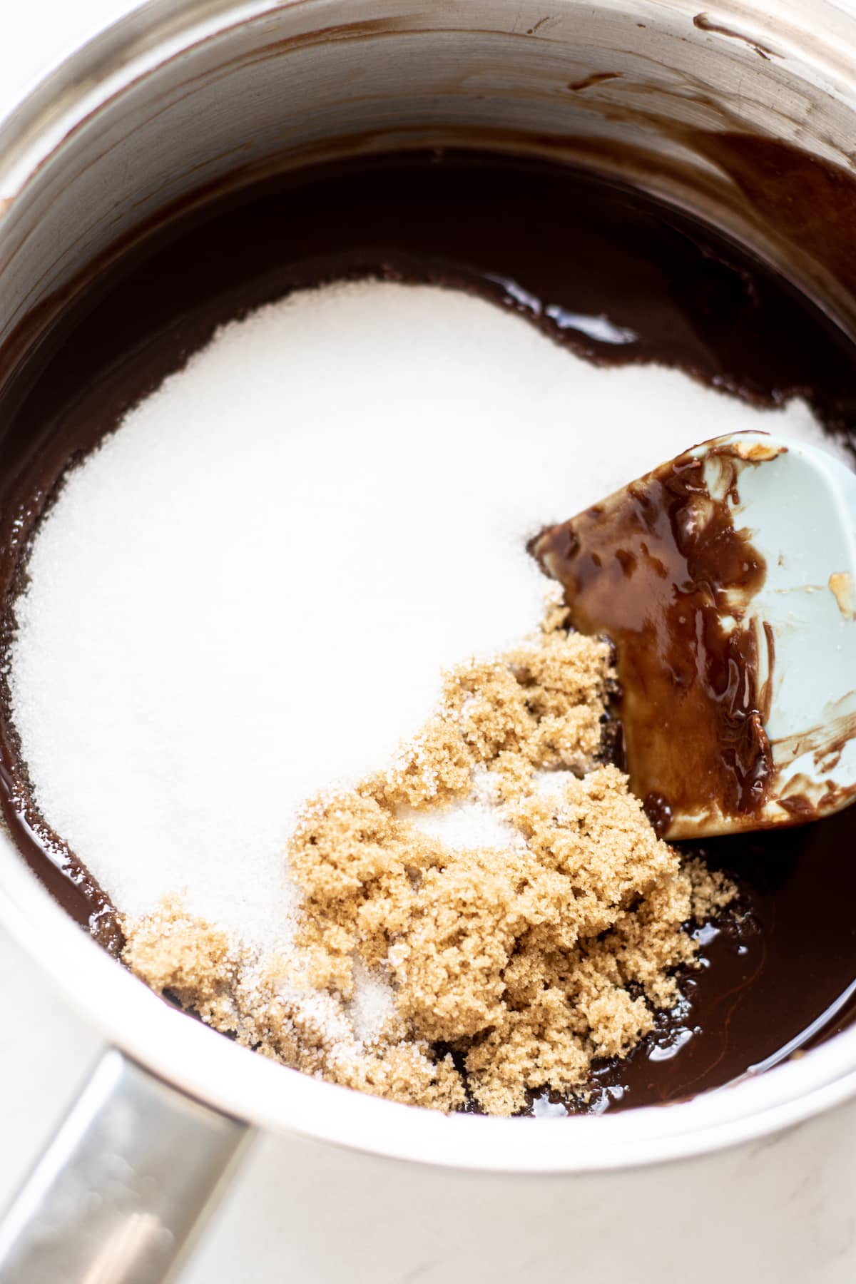 A pot of melted butter and chocolate, white sugar and soft brown sugar