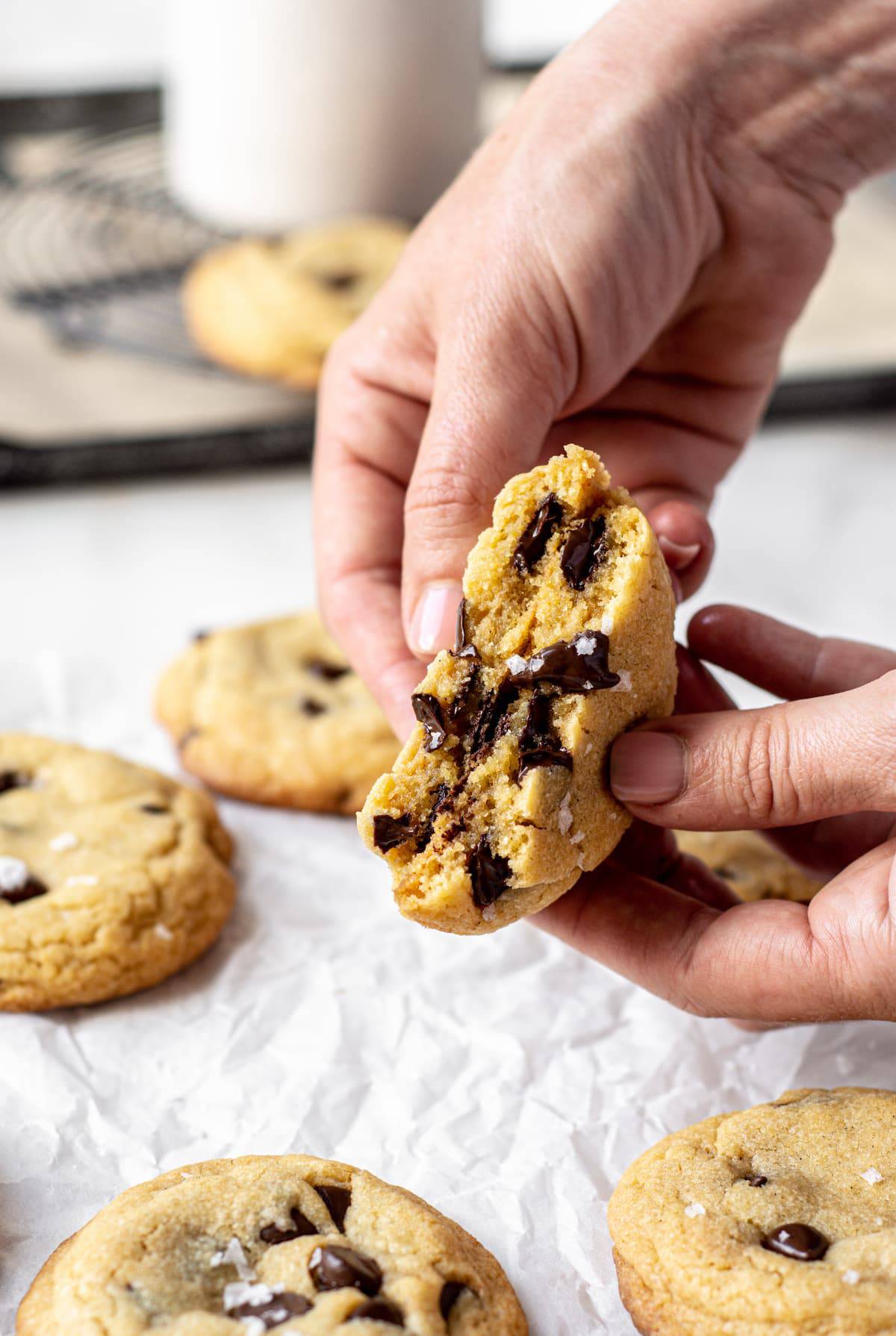 a hand breaking open a chocolate chip cookie