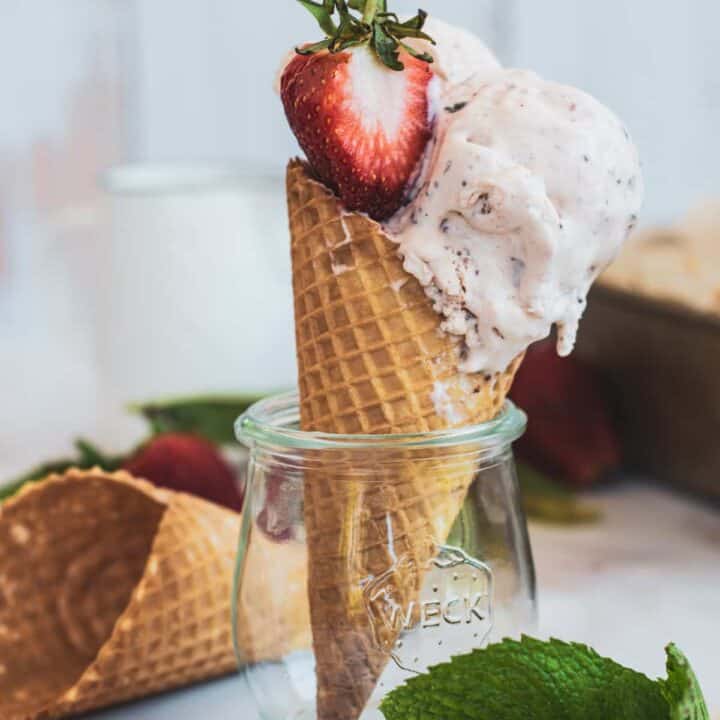 an ice cream cone balanced in a jar with a strawberry on it