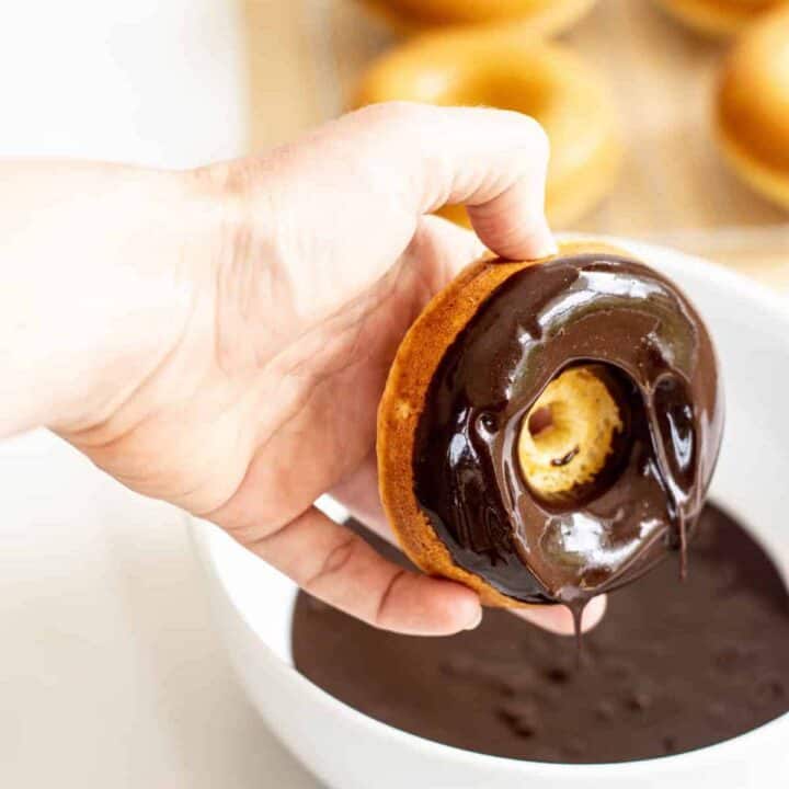 A hand holding a chocolate donut