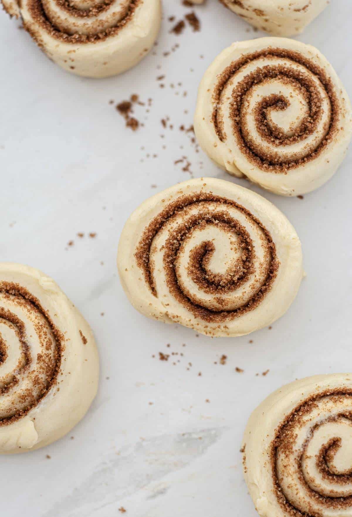 Uncooked easy eggless cinnamon rolls on a bench. 