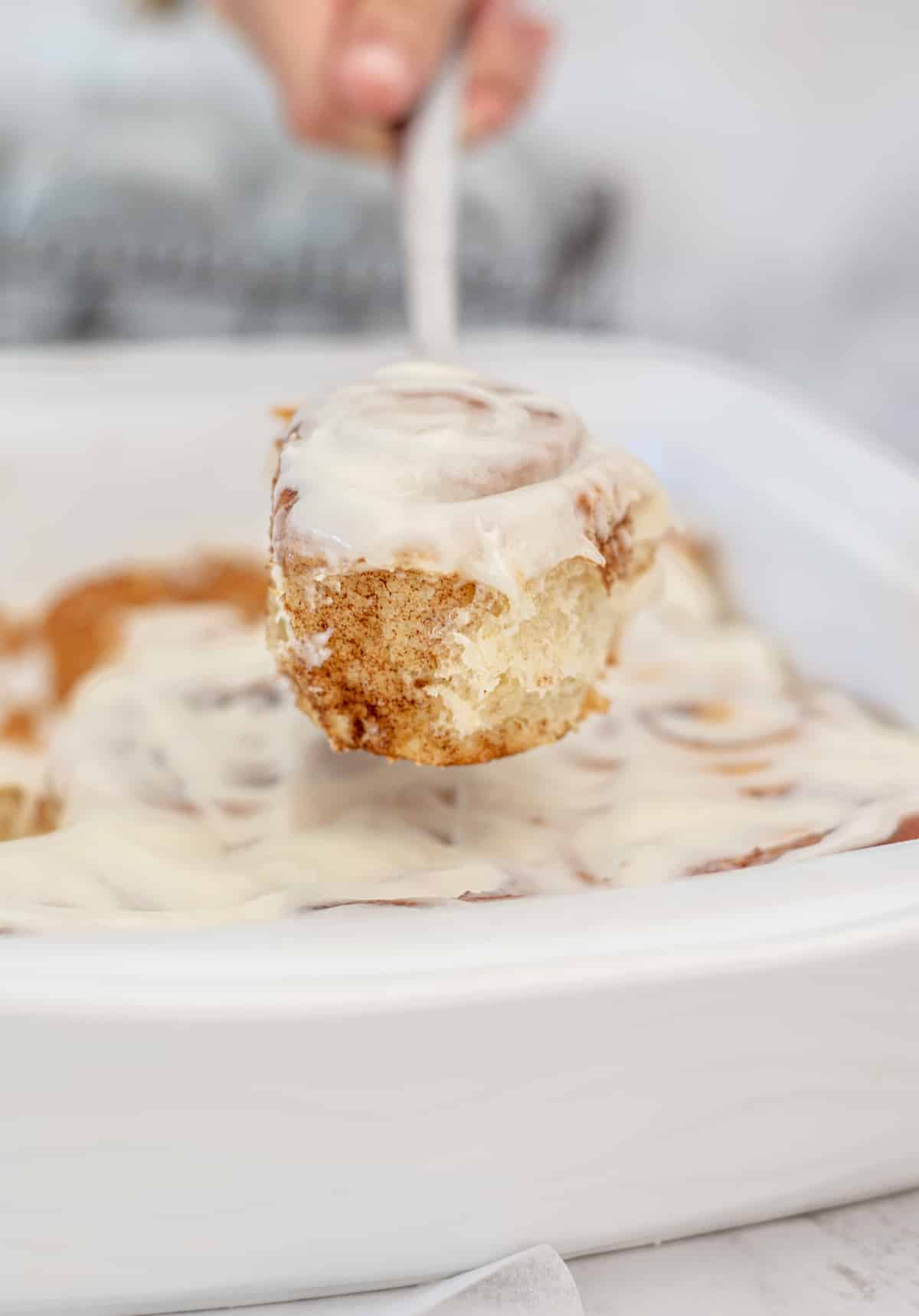 a fork holding a cinnamon roll up in the air.