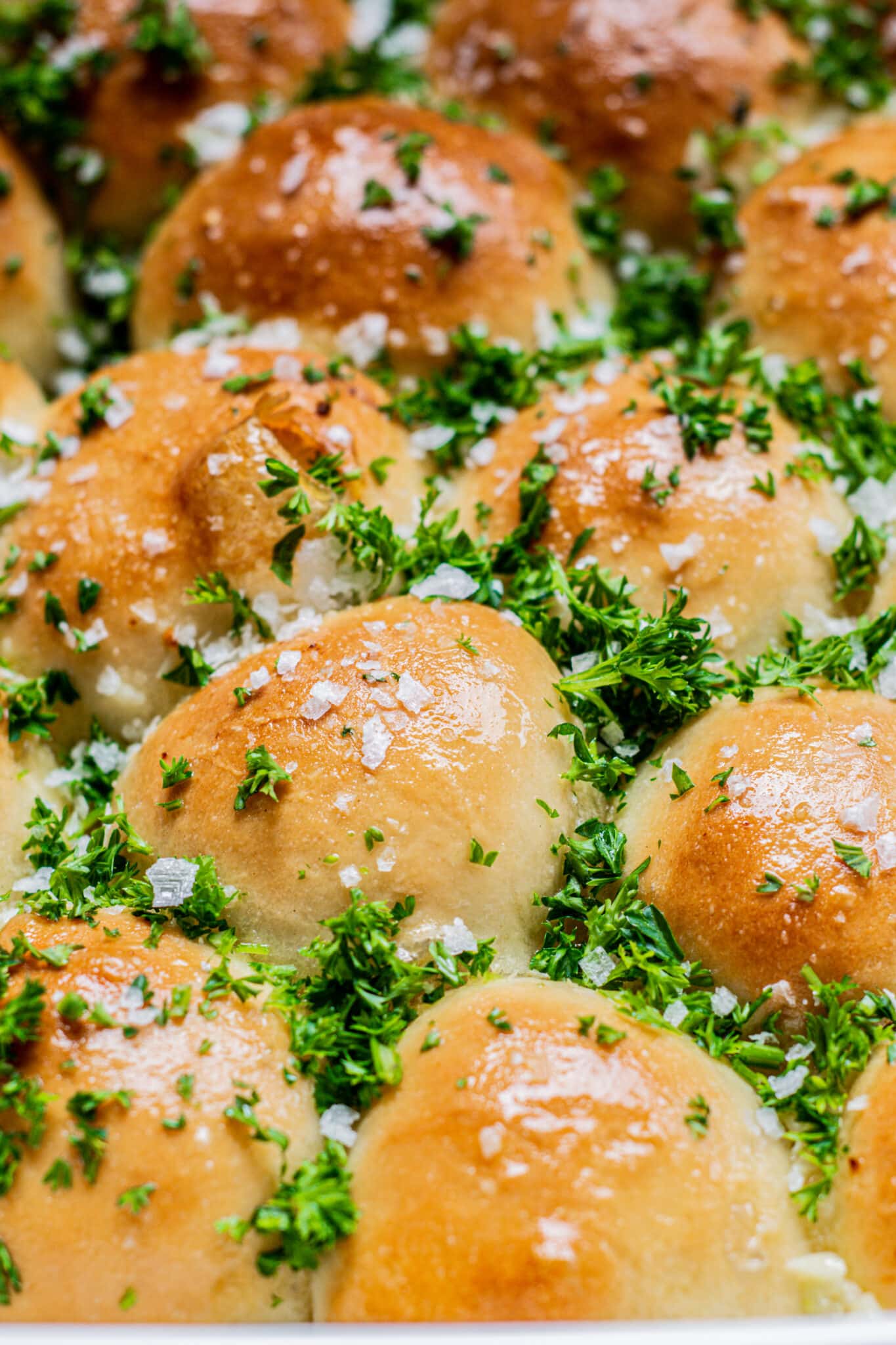 a tray of baked garlic bread bites with green parsley.