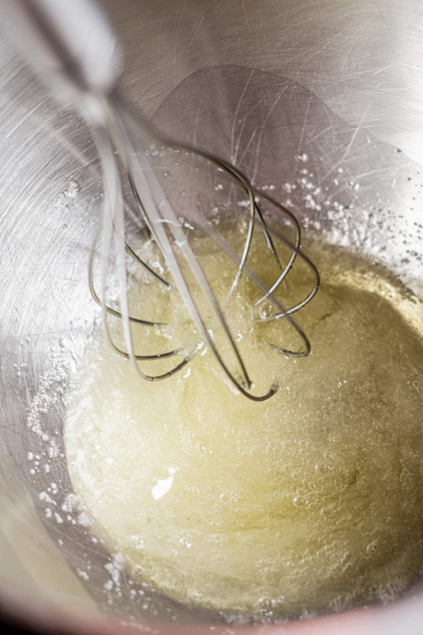 a bowl with egg whites and a whisk.