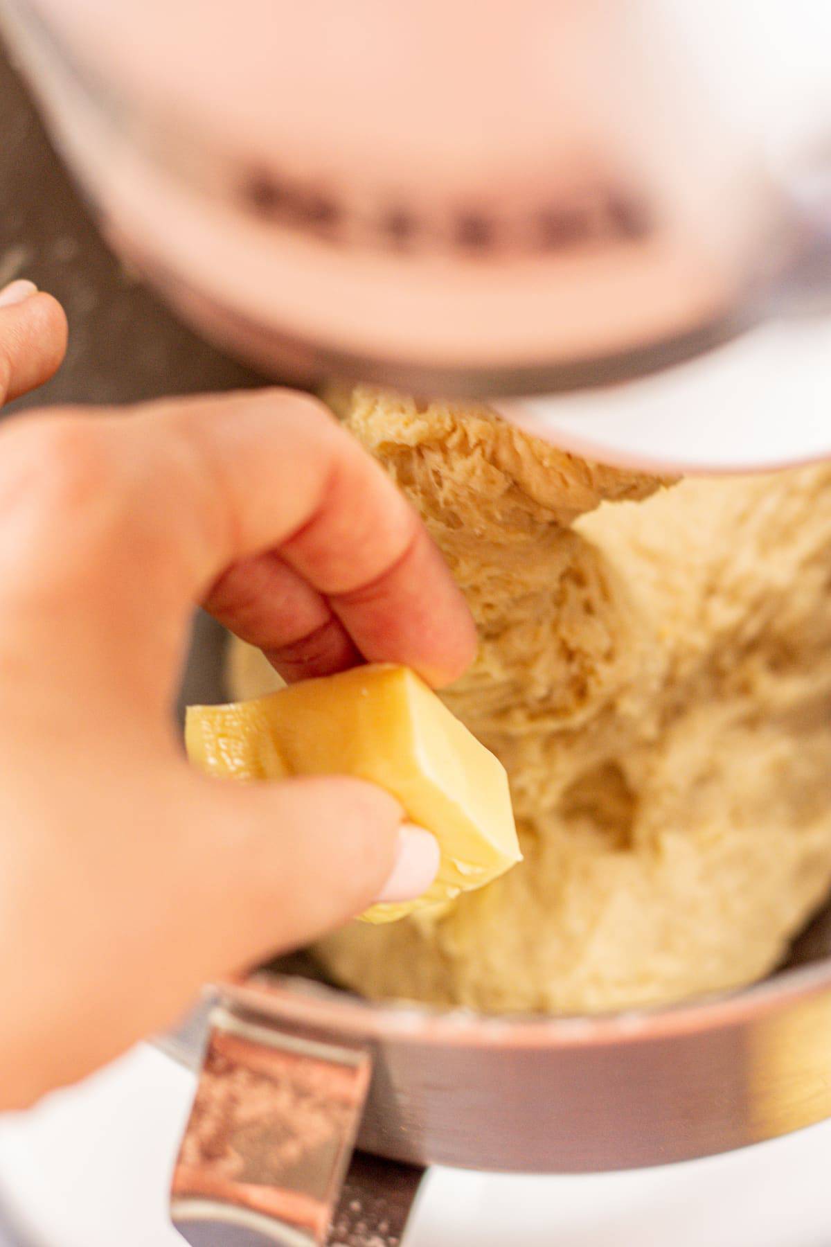 a hand adding cubes of butter into a bowl.