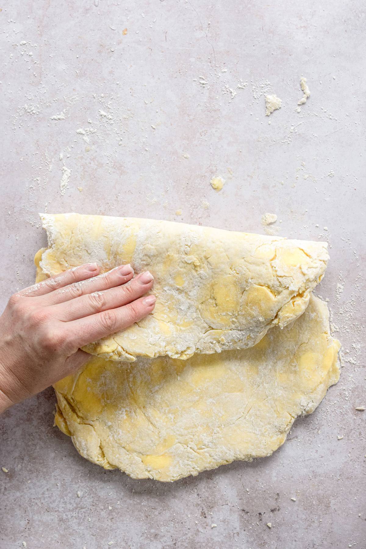 a hand folding over dough.