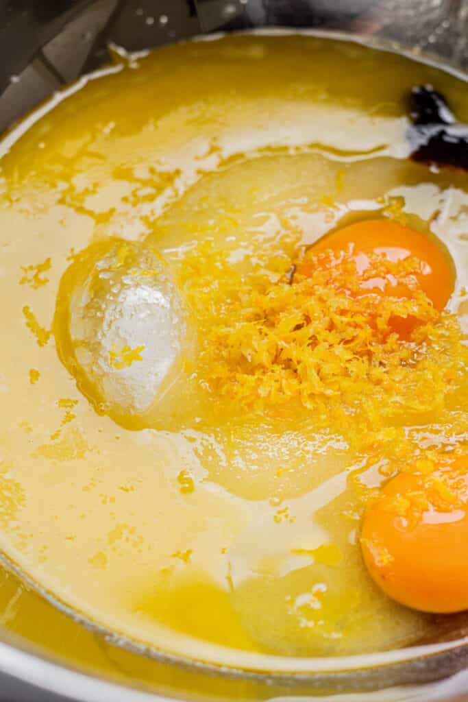 a bowl of eggs, lemon zest, melted butter and sugar.