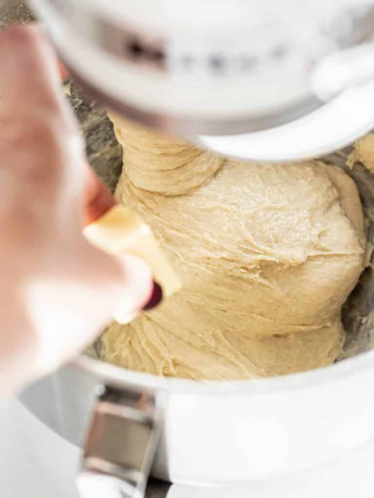 a hand adding butter to dough.