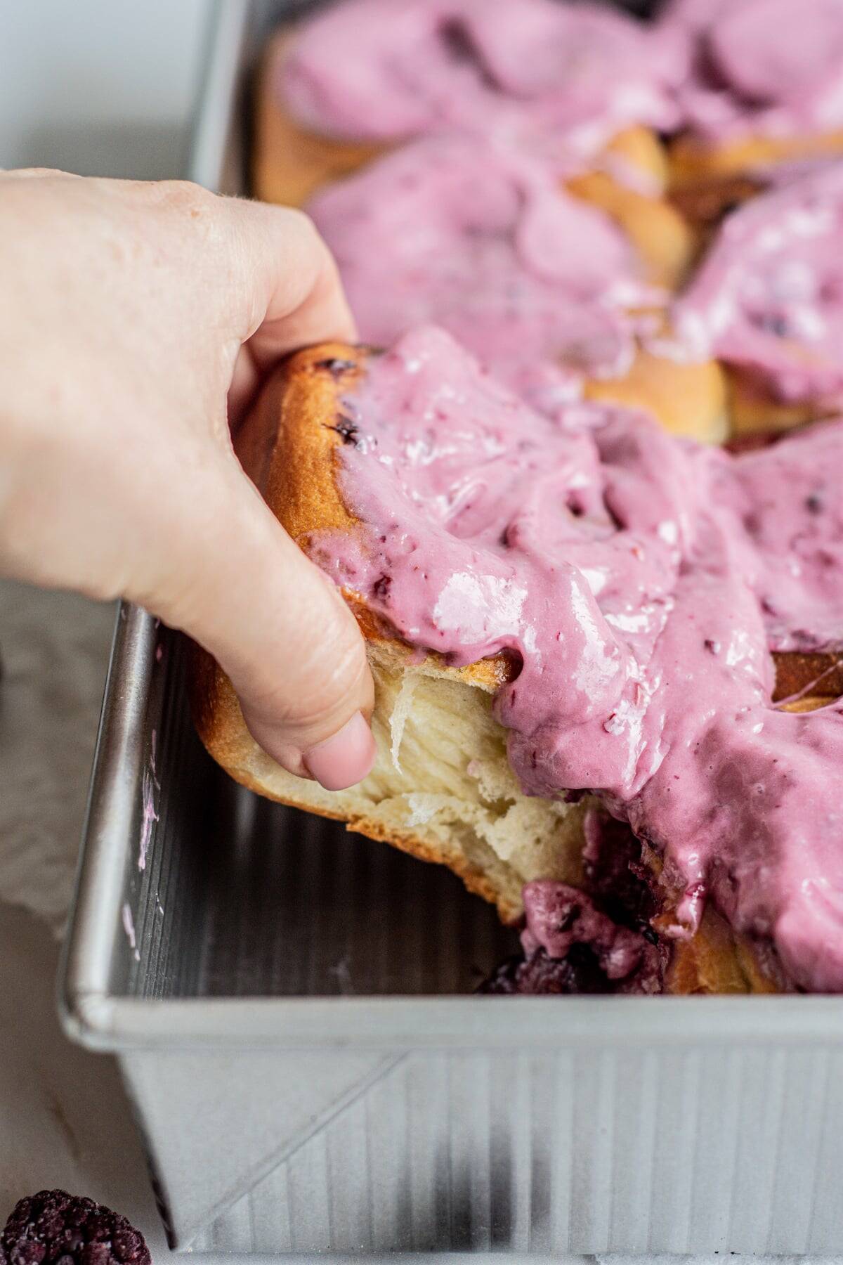 a hand pulling a purple frosted roll.