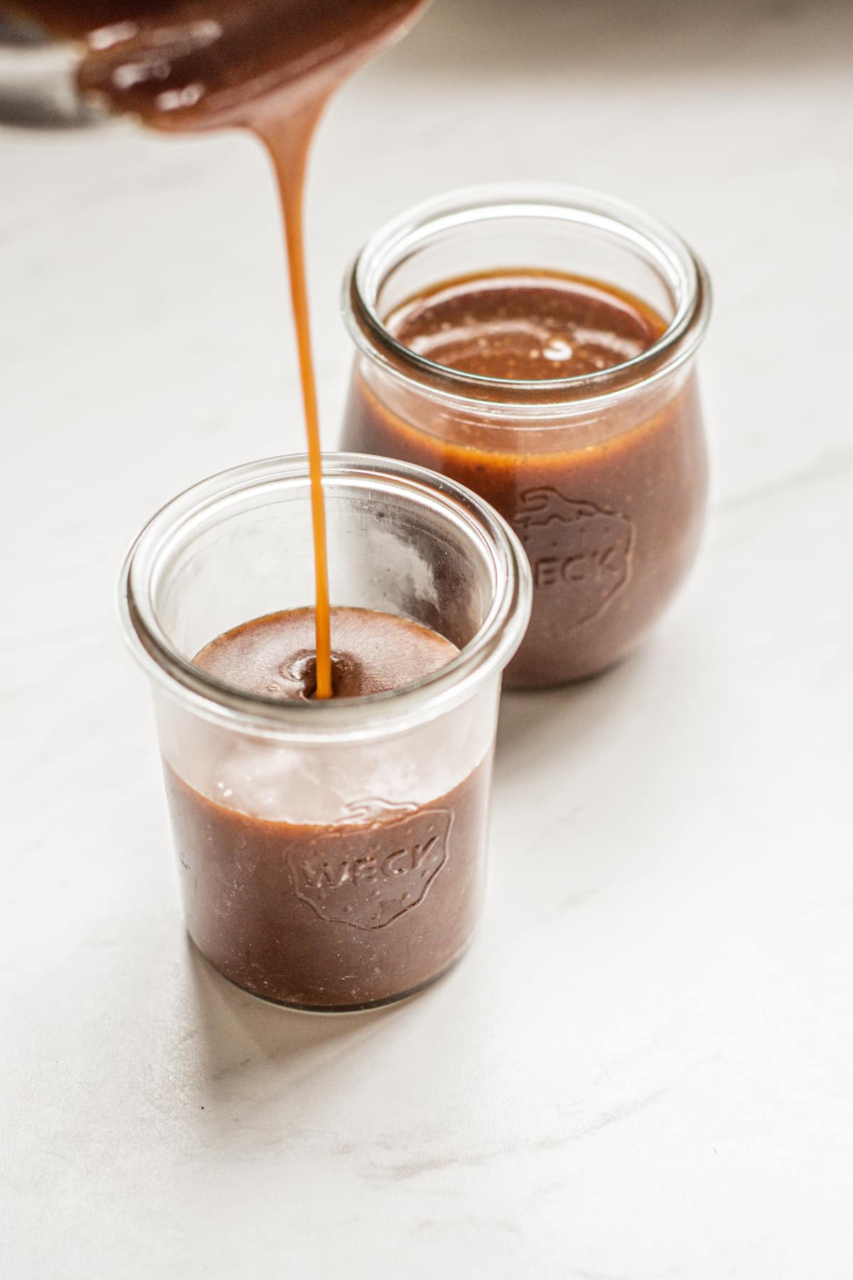 caramel sauce being poured into jars.