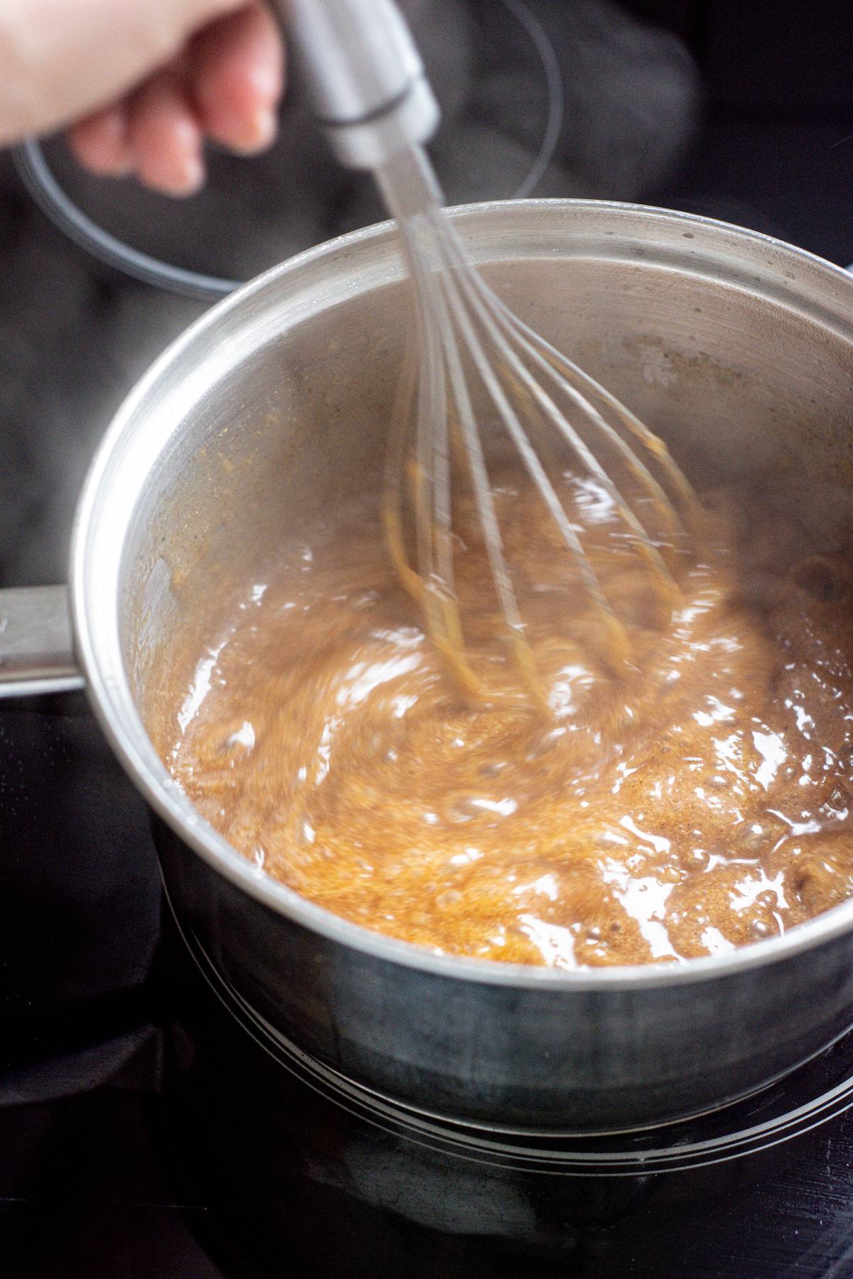 whisking brown caramel in a saucepan.