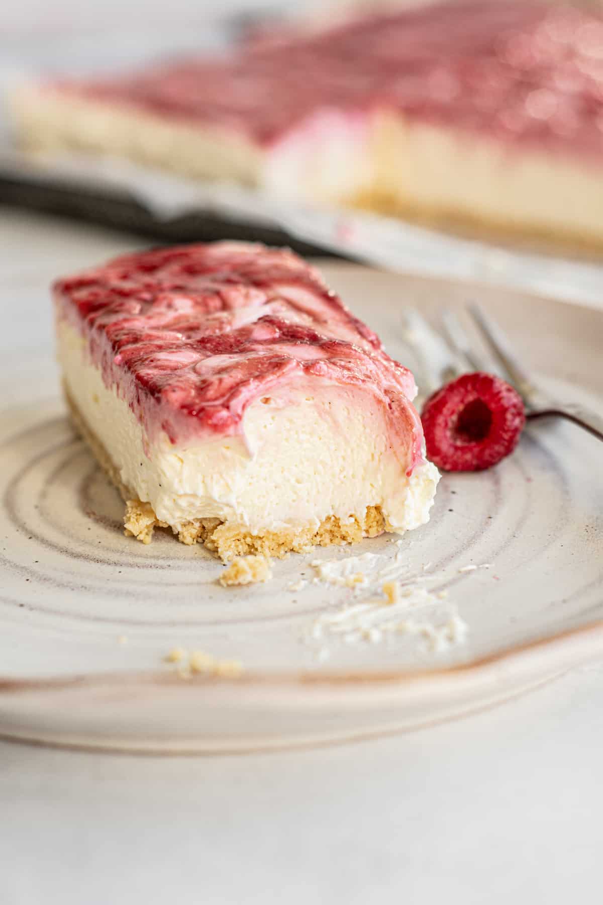 a slice of cheesecake with raspberry next to it.