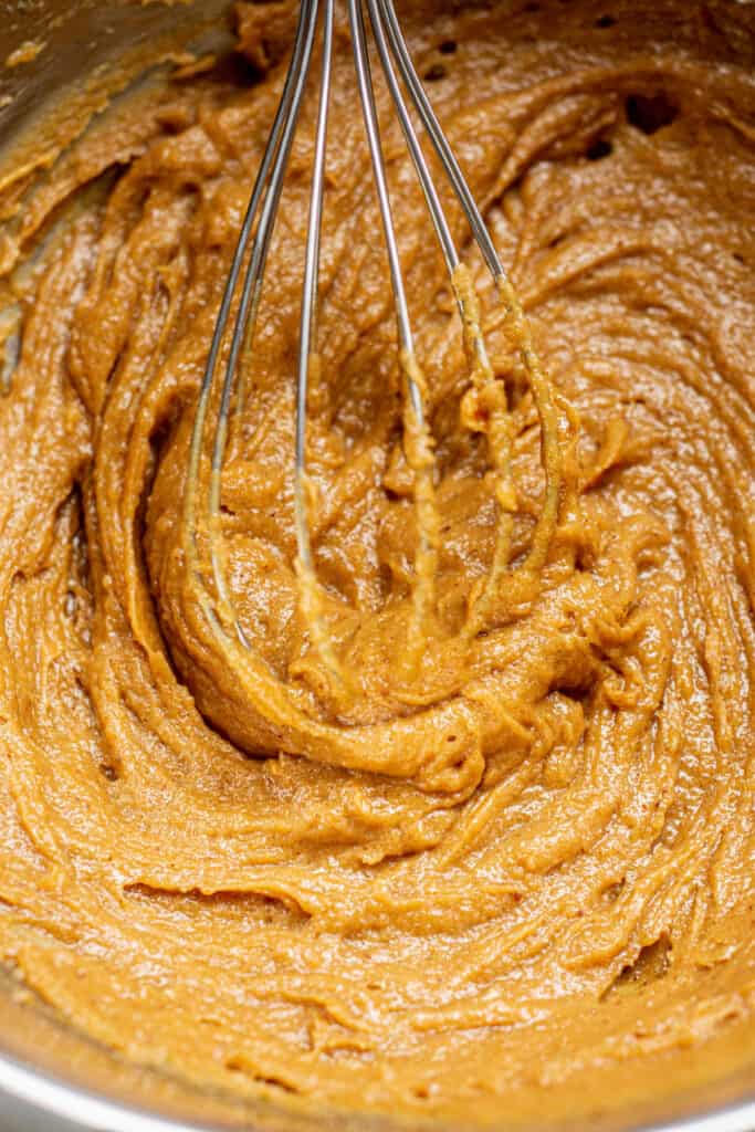a whisk in a brown batter.