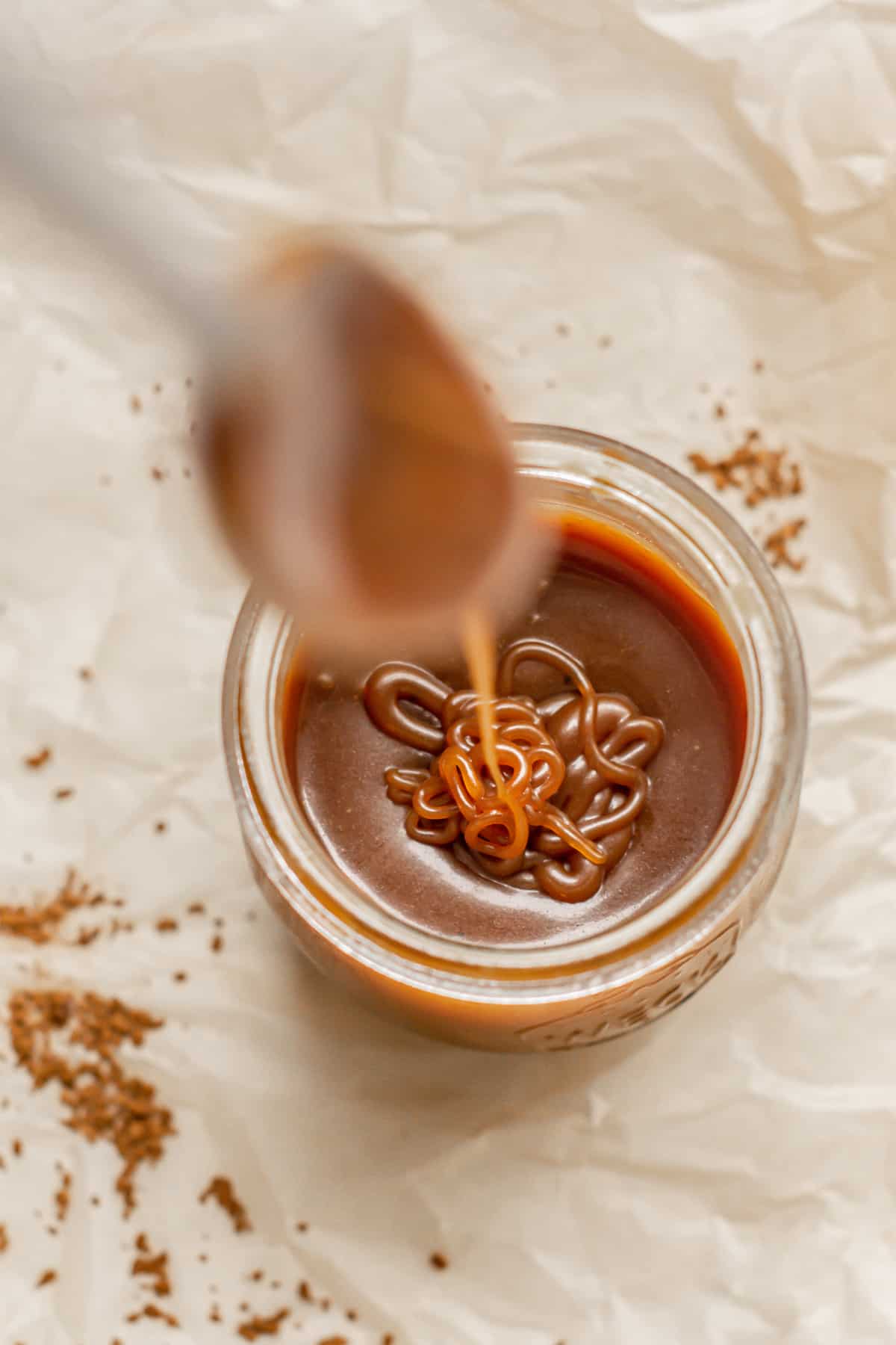spoon drizzling caramel in a jar.