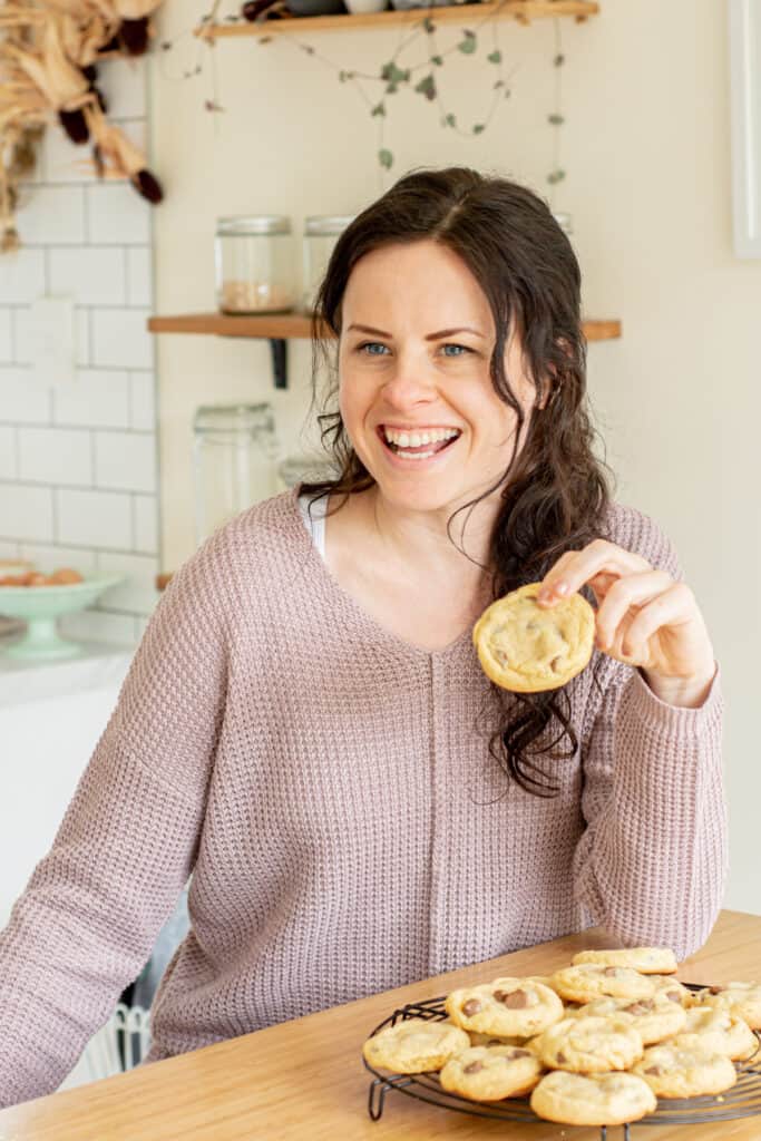 girl in a kitchen holding a cookie.