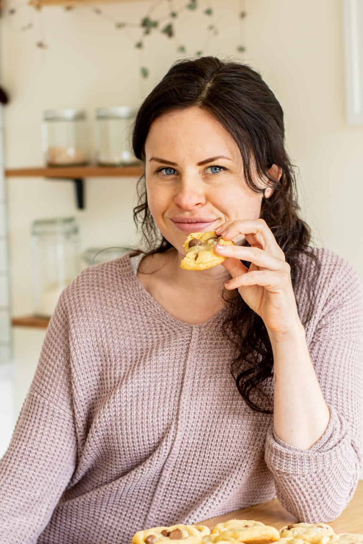 girl in a kitchen holding a cookie.