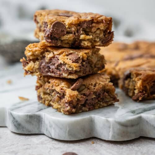 A stack of three oatmeal chocolate chip bars on a marble serving board.