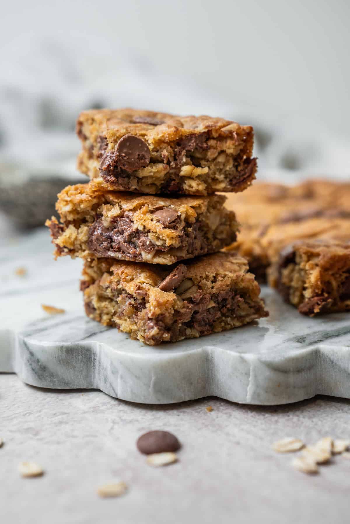 A stack of three oatmeal chocolate chip bars on a marble serving board.