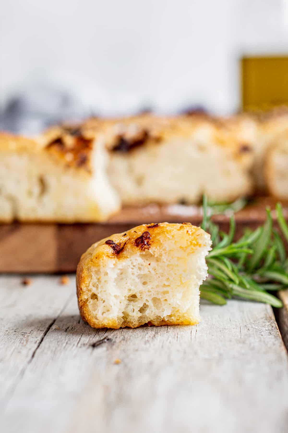 a piece of bitten focaccia with more in the background.