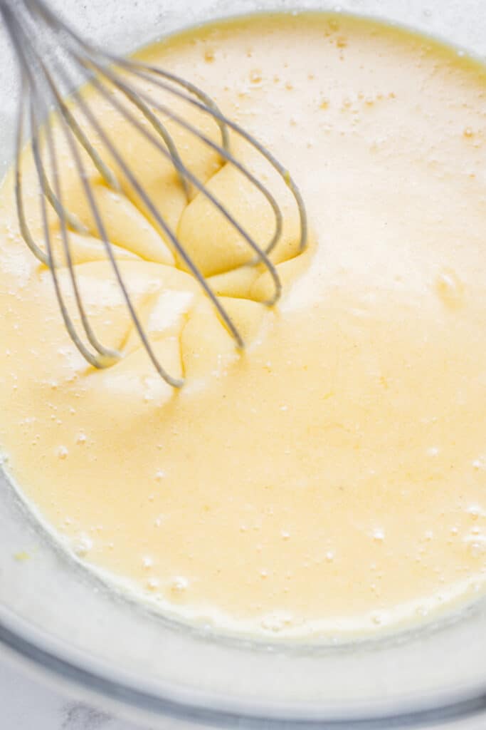 a whisk in yellow batter.