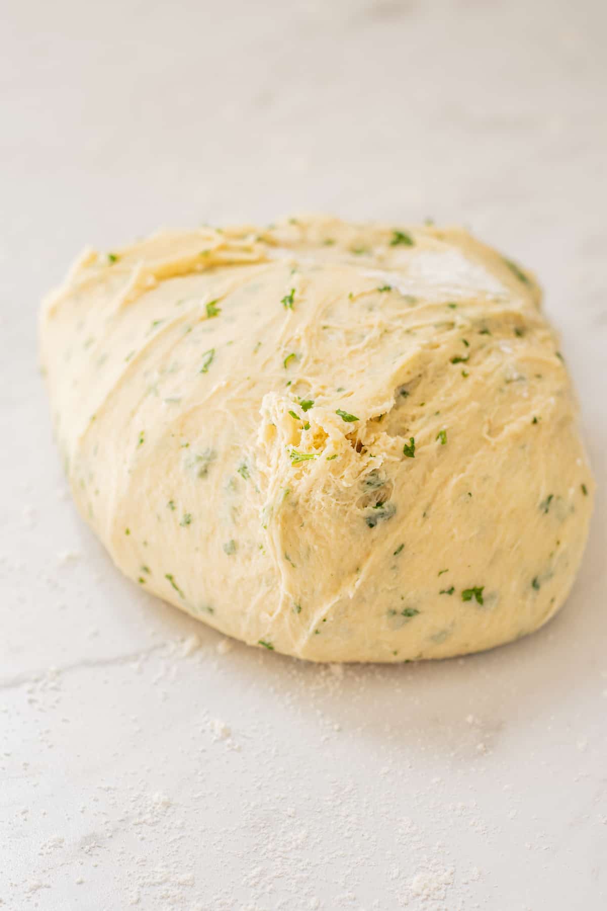 dough on bench with flecks of parsley,
