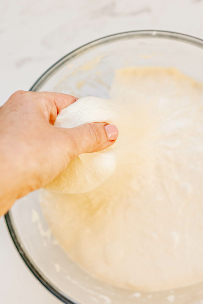 a hand pulling dough.