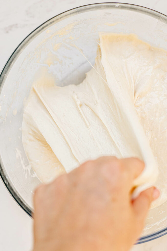 a hand stretching dough.