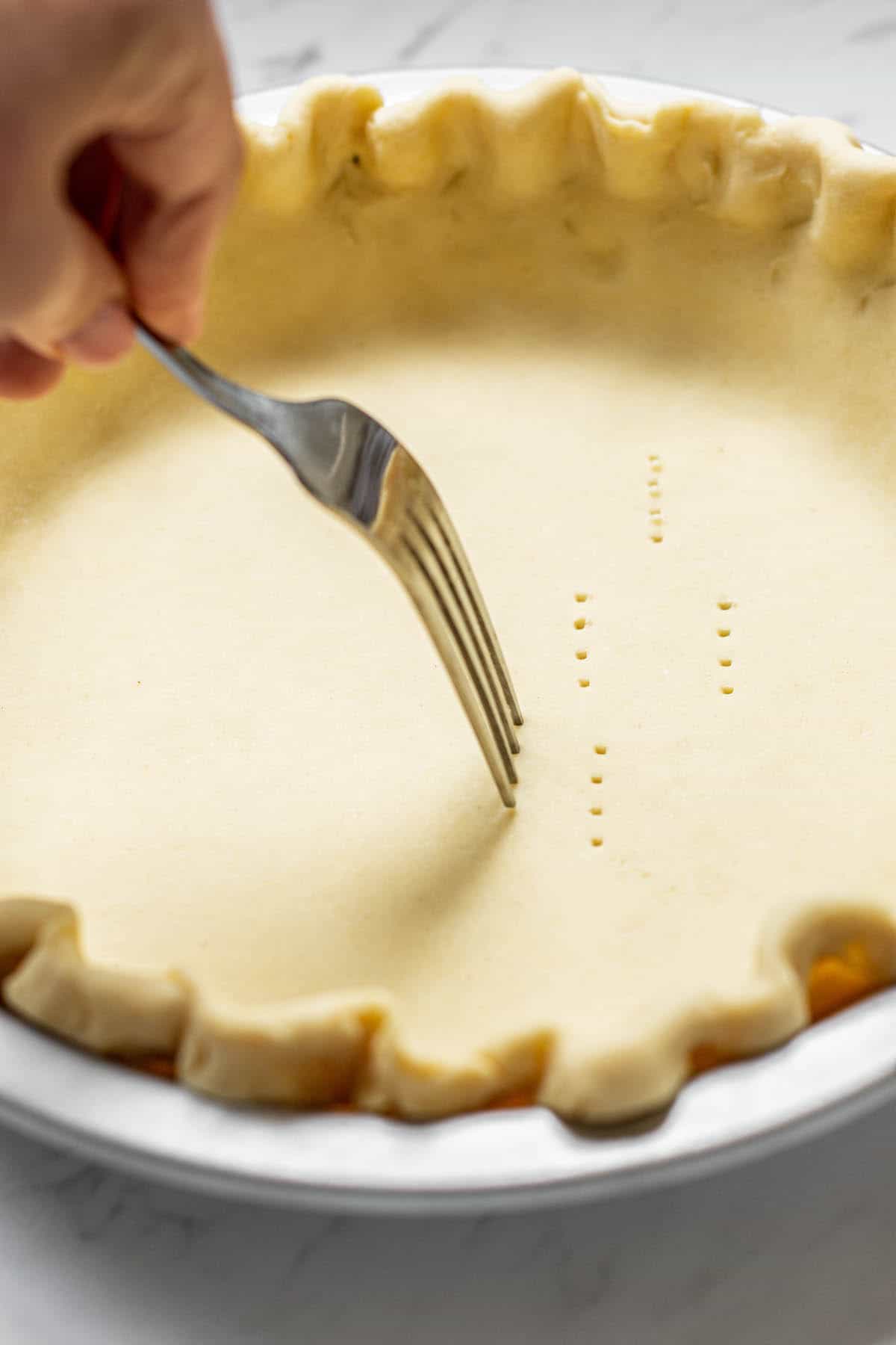 a fork pricking pie crust.
