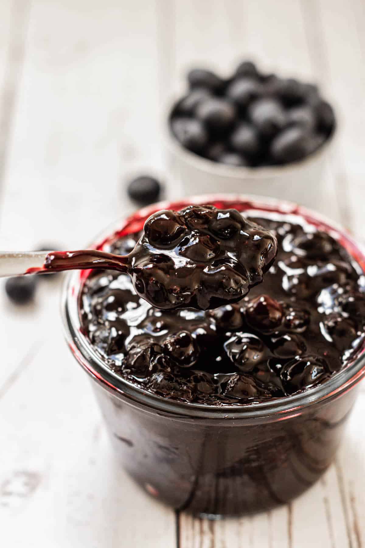 spoon in a jar of blueberry cake filling.