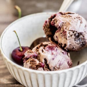 a bowl with 2 scoops ice cream and a cherry.