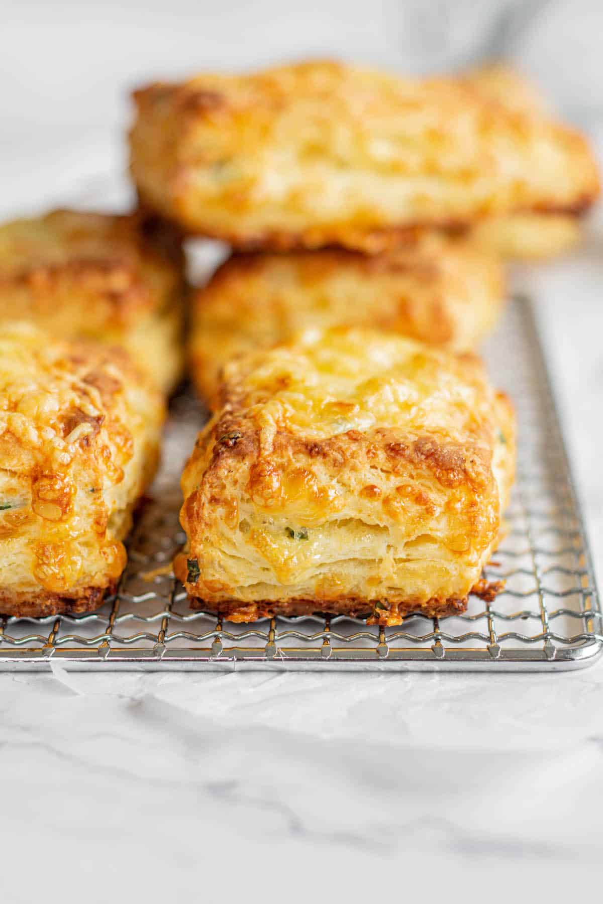 close up of fluffy cheese scones on a wire rack.