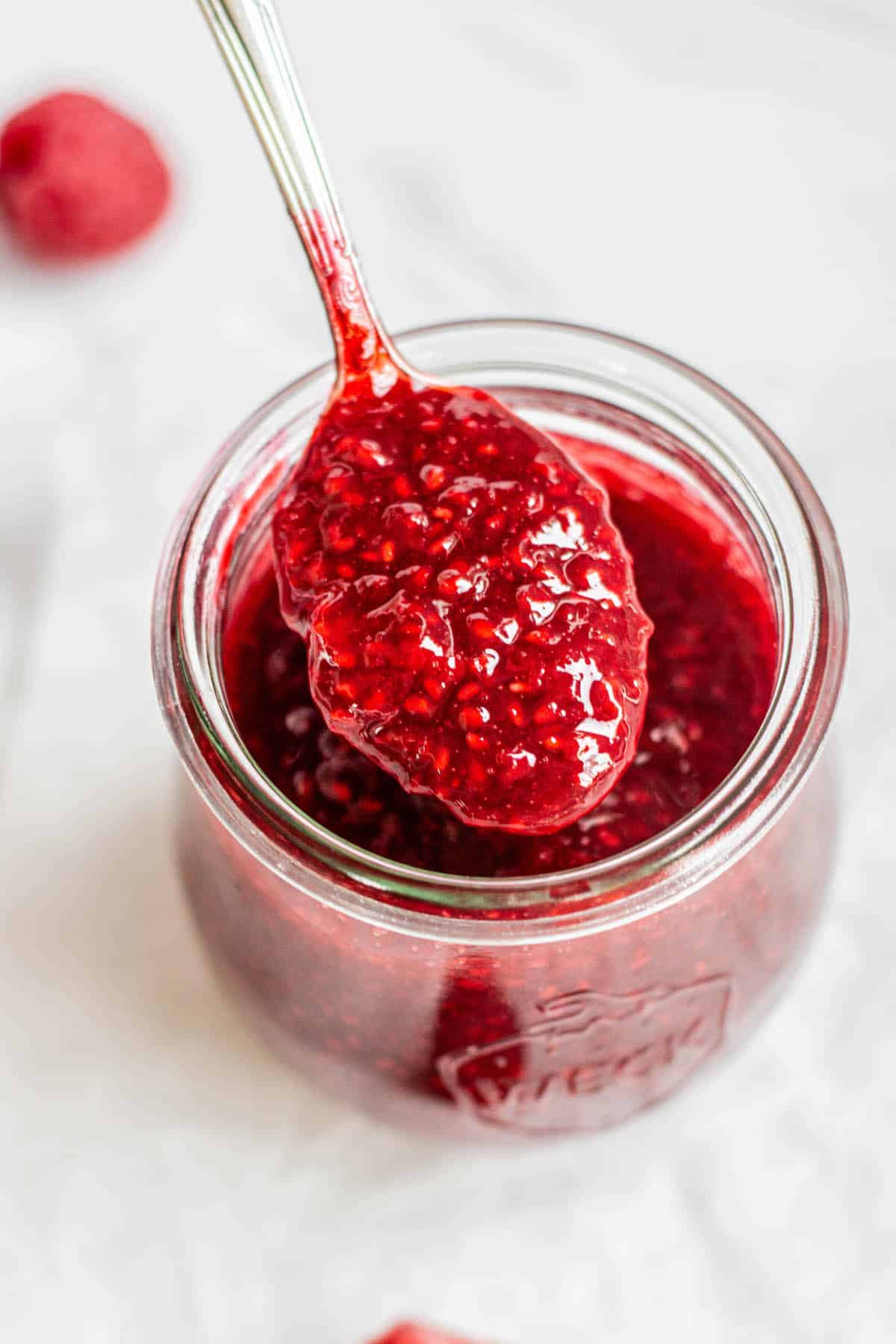 frozen raspberry compote in a jar with a silver spoon.