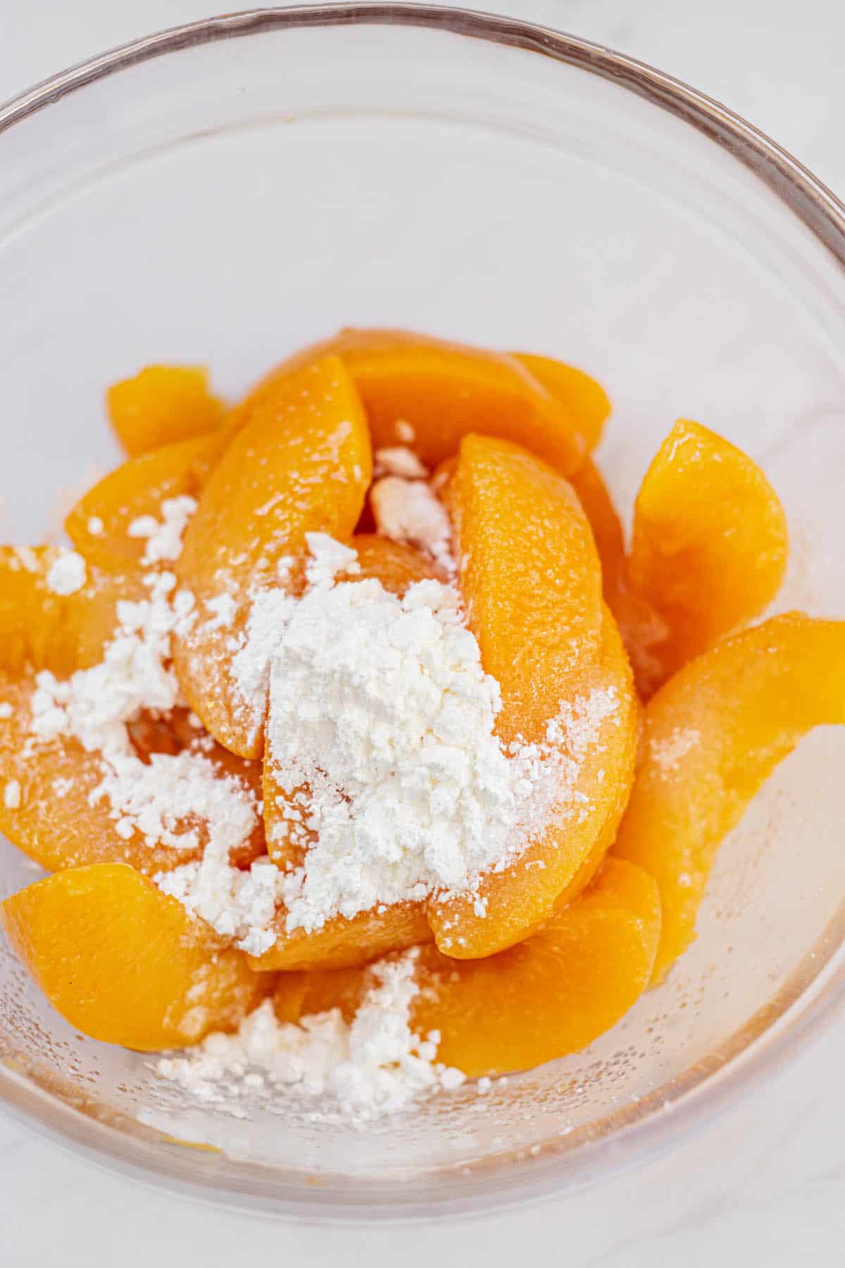 a bowl of canned peaches and powdered sugar.