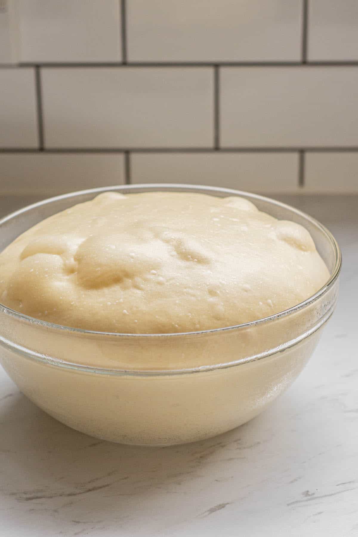 risen dough in a glass bowl.