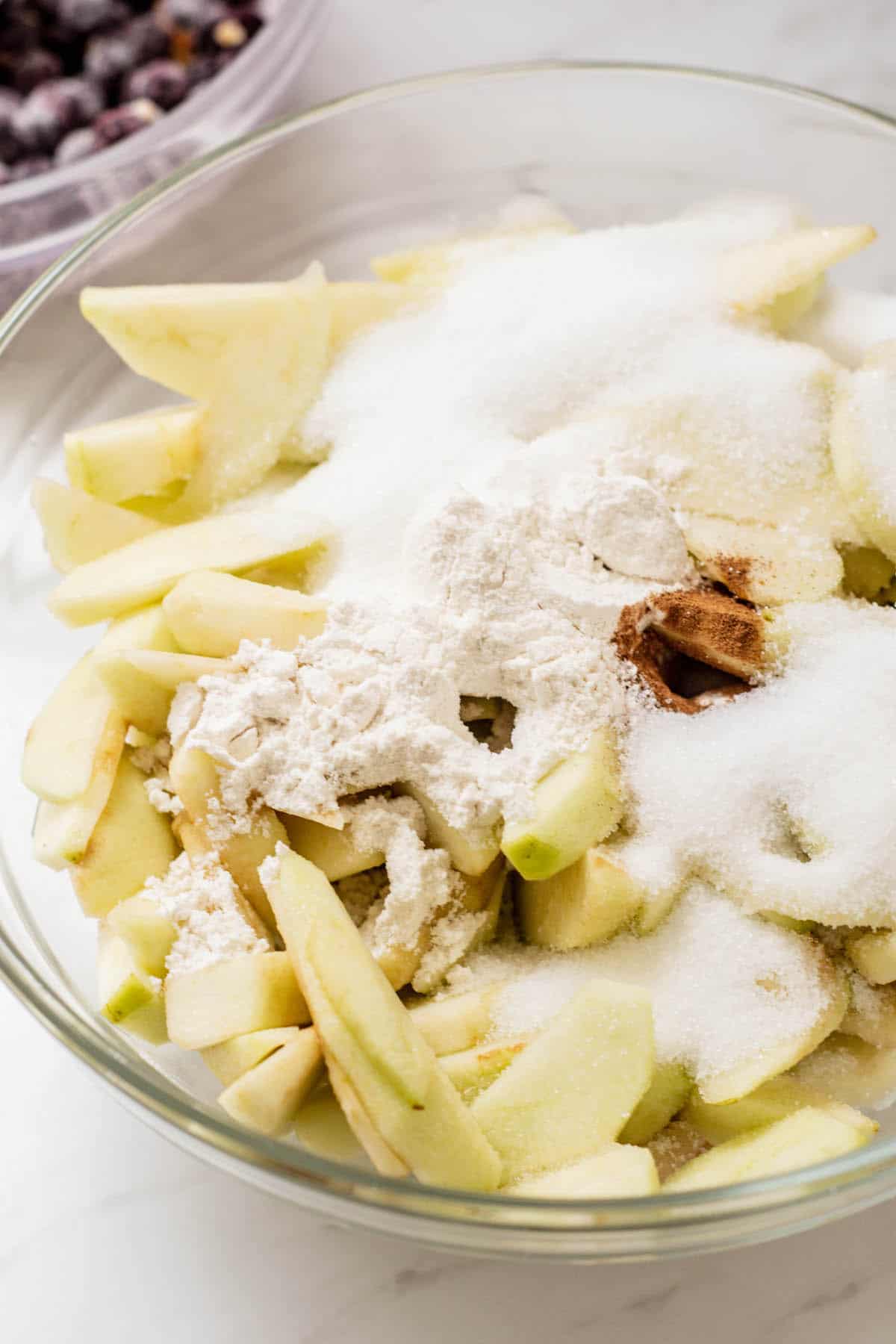 sliced apples in a bowl with spices and flour.