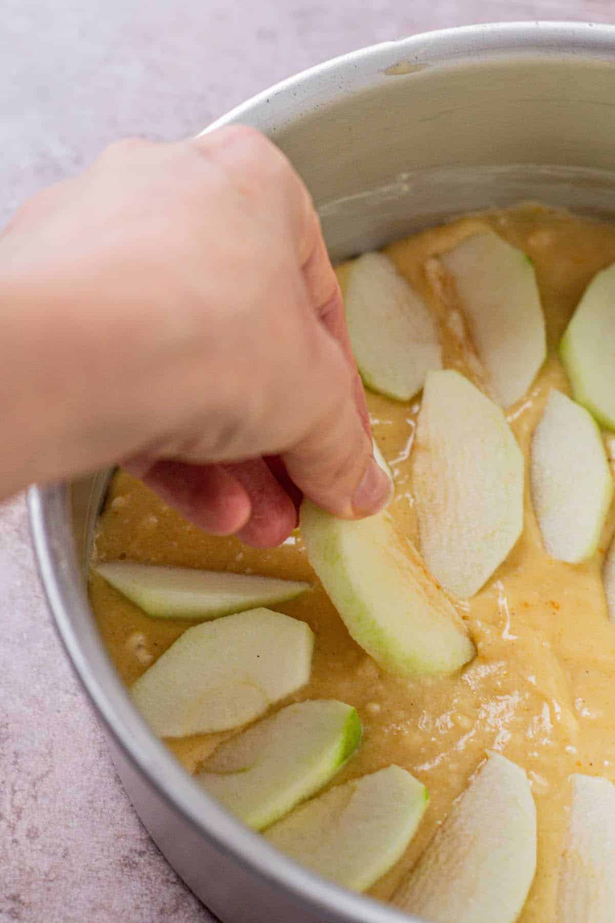 placing apple slices on dutch apple cake.