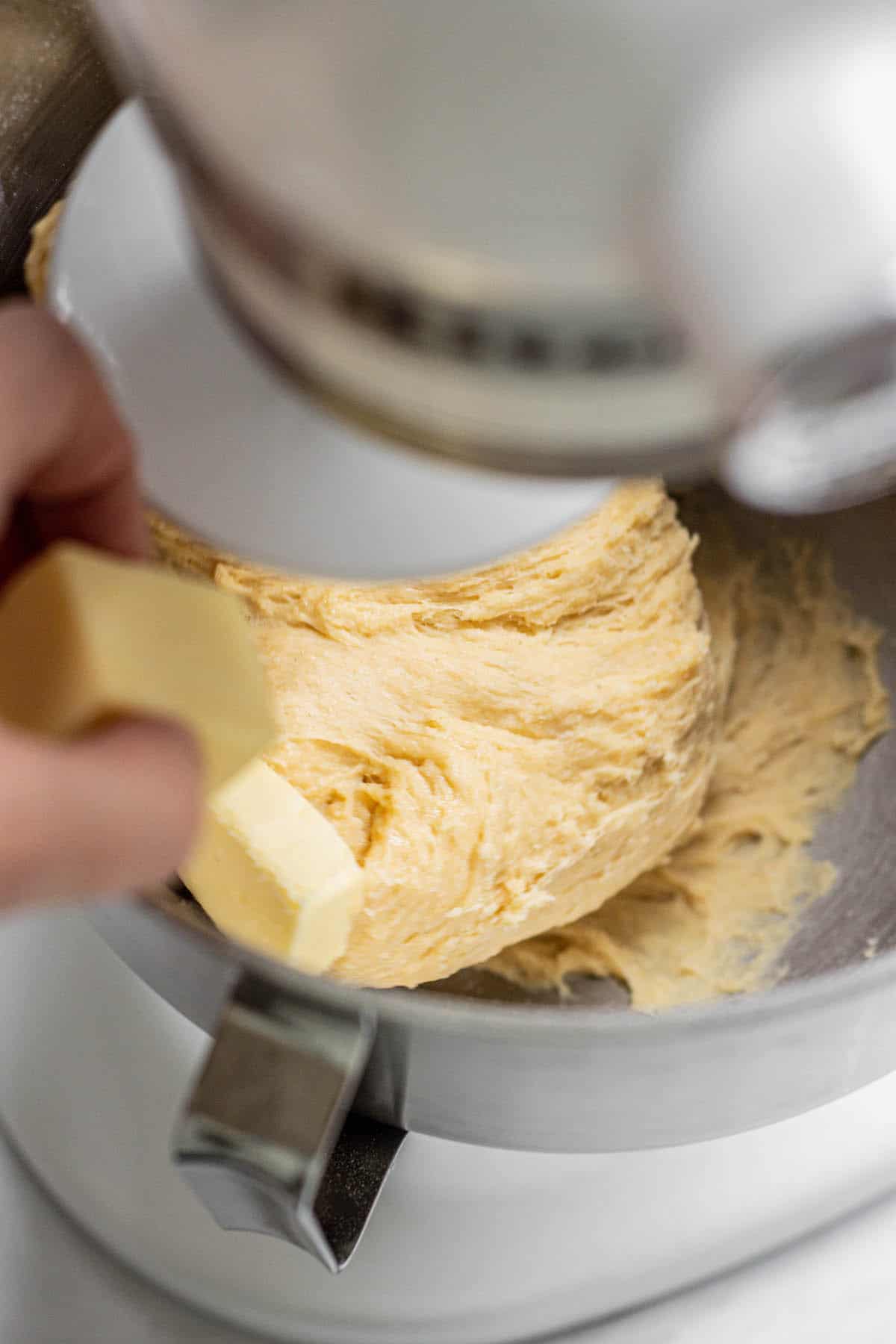 hand putting butter cube in mixer.