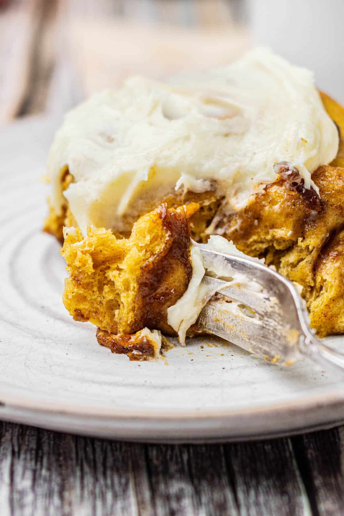 Close up of pumpkin cinnamon rolls on a plate with a fork.