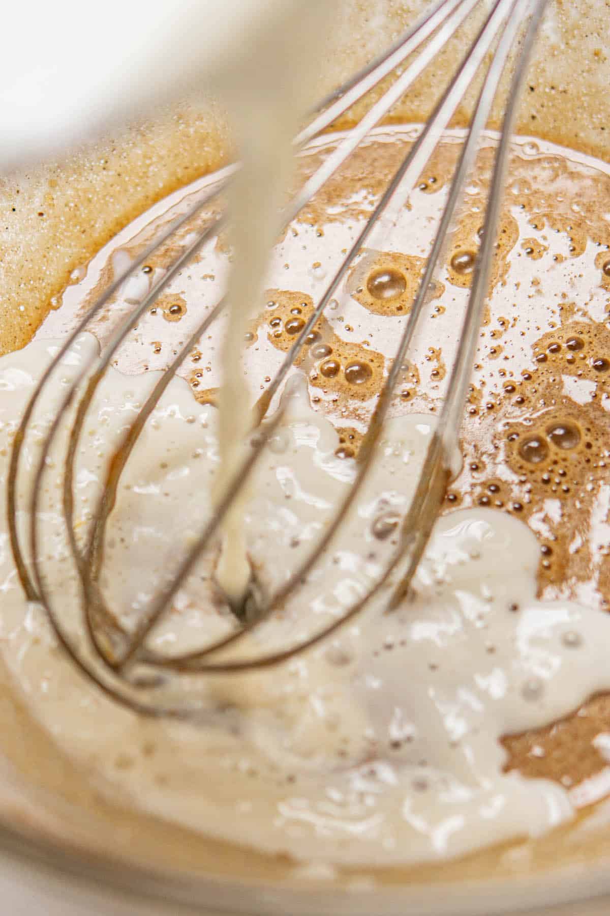 hot milk tempering eggs in a glass bowl.