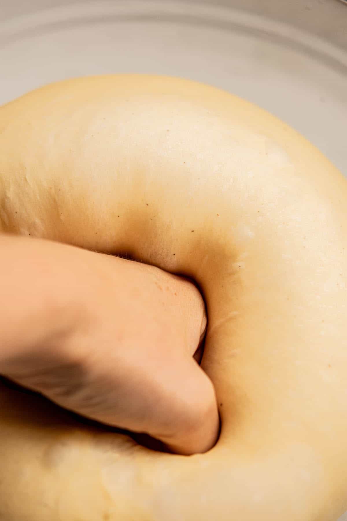 hand punching down dough.