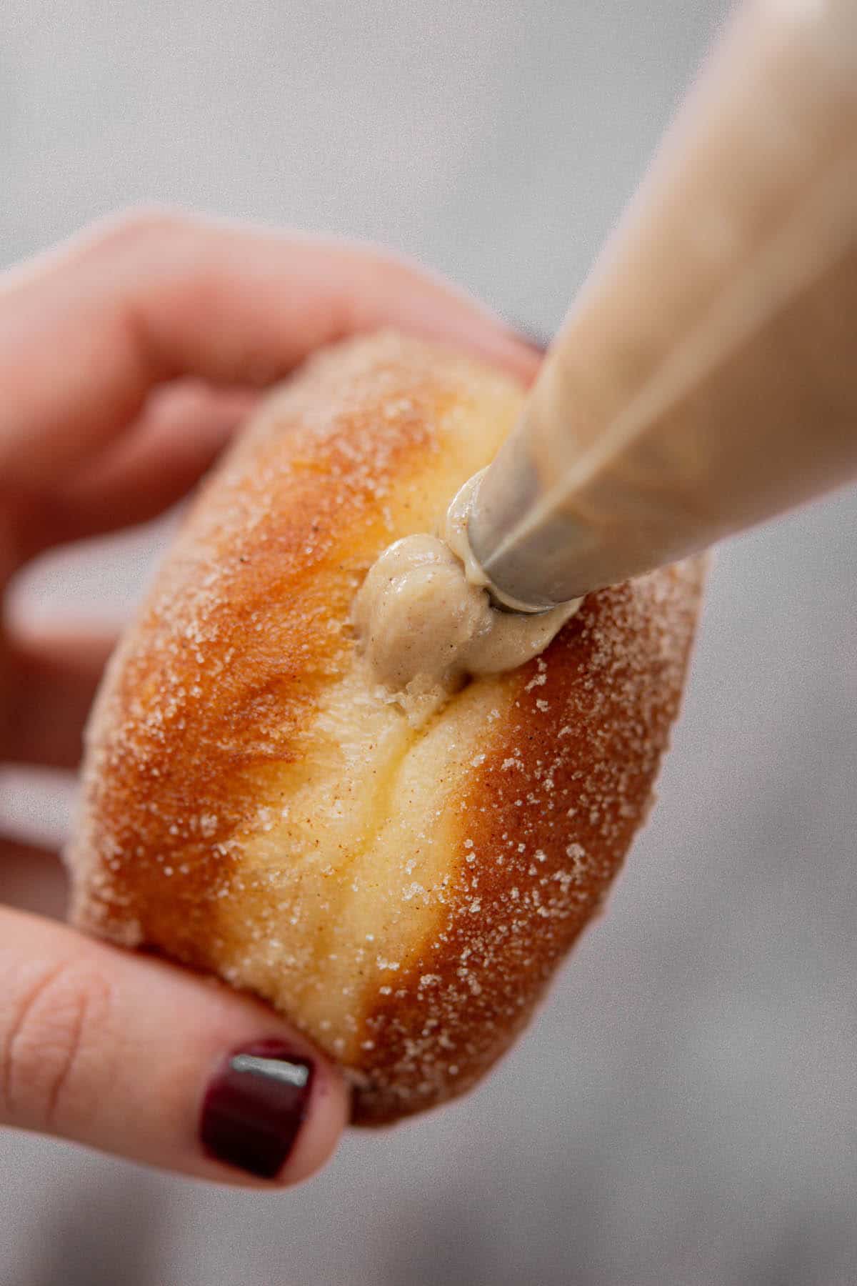 gingerbread custard being piped into doughnut.